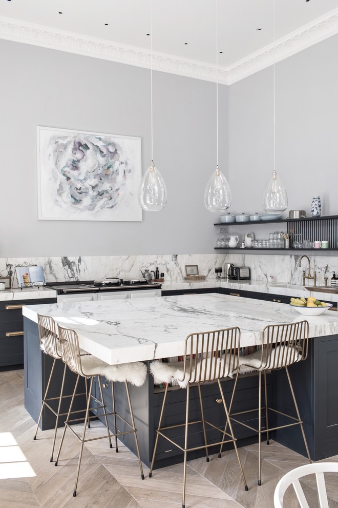 This is an example of a mid-sized transitional l-shaped kitchen in Dorset with shaker cabinets, blue cabinets, marble benchtops, grey splashback, marble splashback, with island, beige floor and grey benchtop.