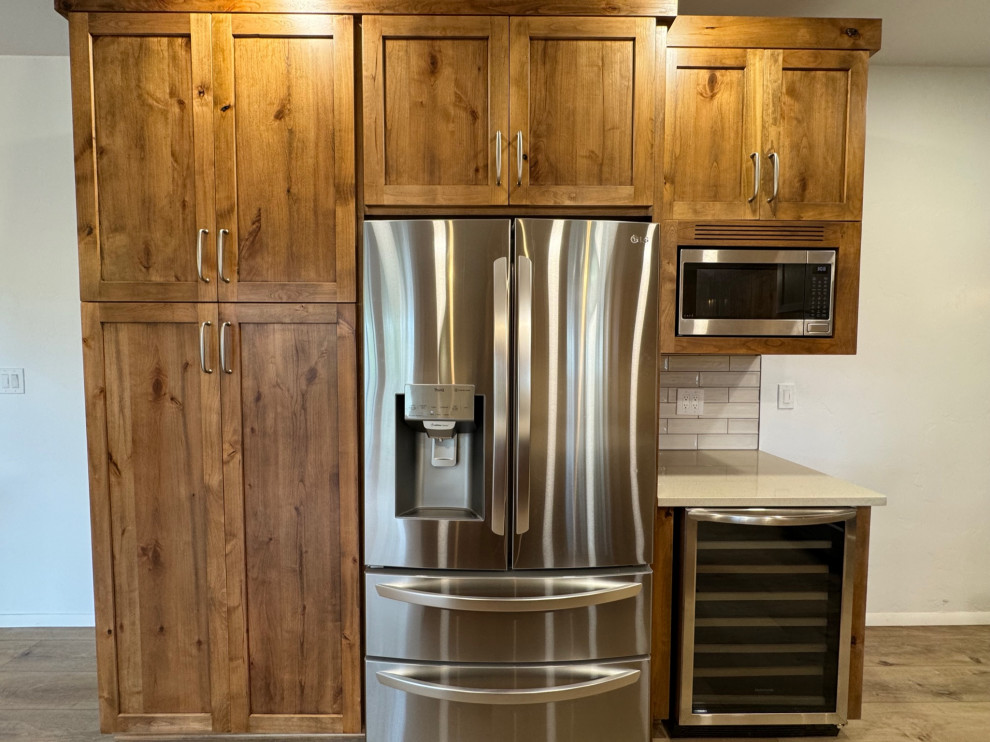 Example of a mid-sized transitional u-shaped laminate floor and beige floor eat-in kitchen design in Phoenix with a farmhouse sink, shaker cabinets, medium tone wood cabinets, quartz countertops, white backsplash, porcelain backsplash, stainless steel appliances, an island and beige countertops