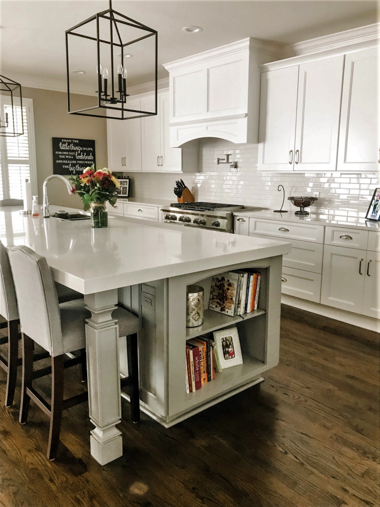 Mid-sized transitional single-wall open plan kitchen in Atlanta with an undermount sink, shaker cabinets, white cabinets, quartz benchtops, white splashback, subway tile splashback, stainless steel appliances, dark hardwood floors, with island, brown floor and white benchtop.