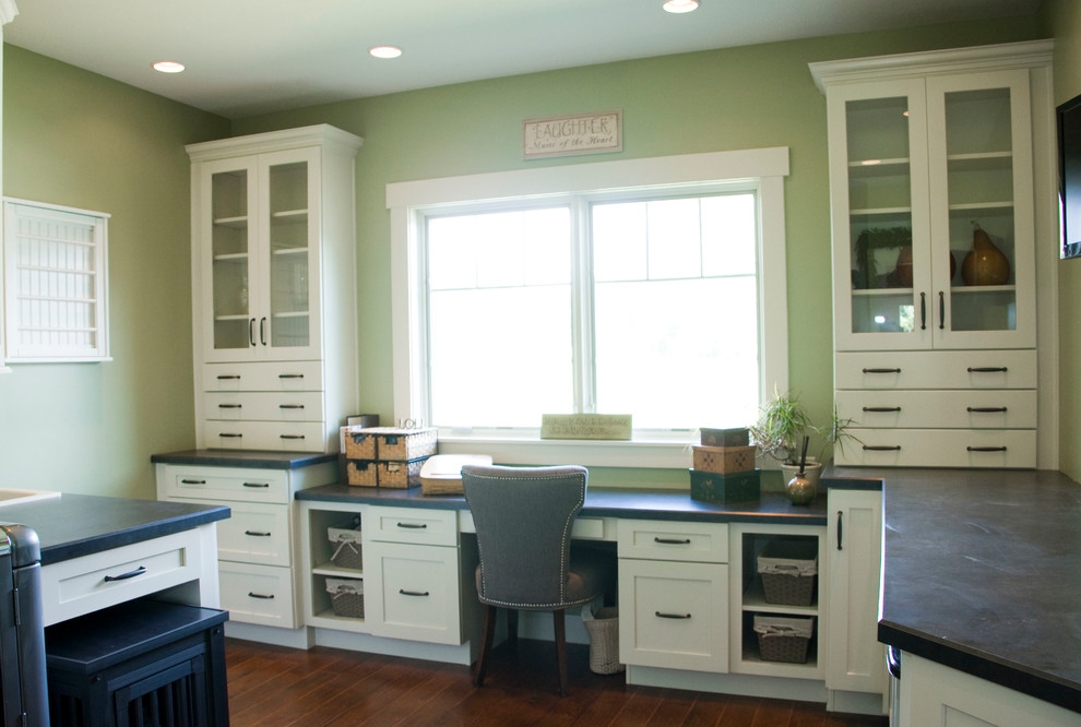 This is an example of a mid-sized traditional utility room in Cincinnati with a drop-in sink, shaker cabinets, white cabinets, laminate benchtops, green walls, medium hardwood floors and a side-by-side washer and dryer.