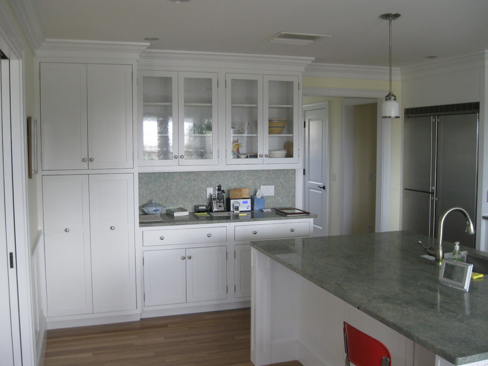 Example of a large transitional galley medium tone wood floor kitchen design in Providence with an undermount sink, white cabinets, granite countertops, green backsplash, stainless steel appliances, an island and shaker cabinets