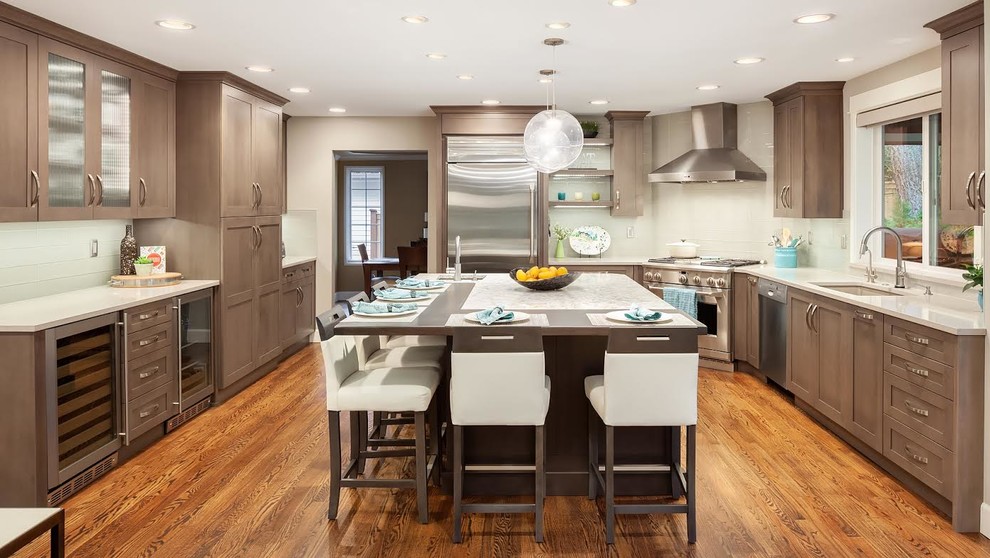 Eat-in kitchen - large transitional u-shaped dark wood floor and brown floor eat-in kitchen idea in Seattle with an undermount sink, recessed-panel cabinets, medium tone wood cabinets, quartz countertops, white backsplash, glass tile backsplash, stainless steel appliances, an island and beige countertops