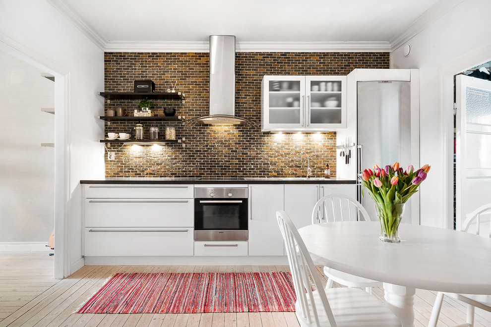 Inspiration for a scandinavian single-wall eat-in kitchen in Copenhagen with flat-panel cabinets, brick splashback, light hardwood floors, no island and beige floor.