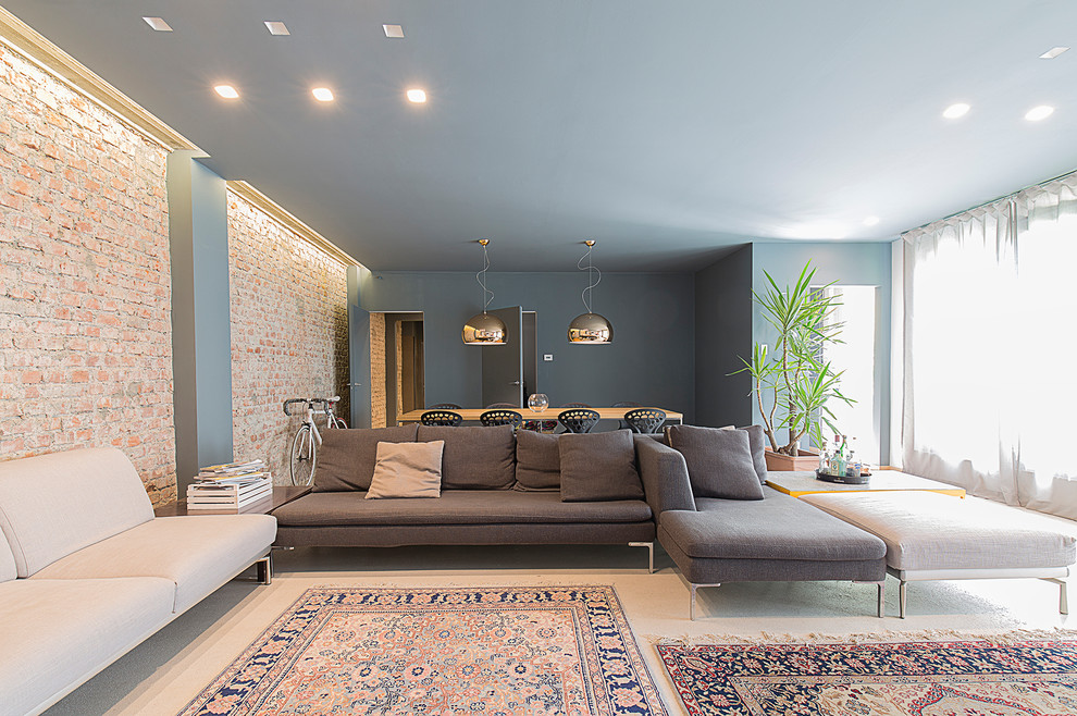 This is an example of a large contemporary open concept living room in Milan with a home bar, multi-coloured walls, concrete floors, a wall-mounted tv and grey floor.