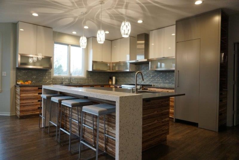Large modern l-shaped open plan kitchen in Indianapolis with an undermount sink, flat-panel cabinets, white cabinets, quartzite benchtops, stainless steel appliances, medium hardwood floors, with island and brown floor.