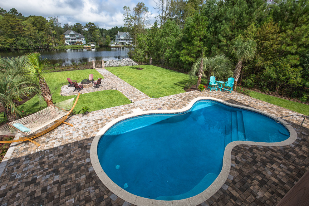 Large transitional backyard concrete paver and custom-shaped pool photo