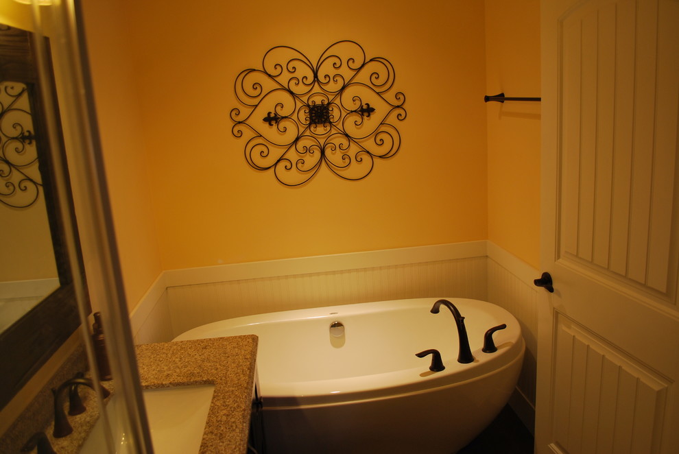 Inspiration for a mid-sized rustic 3/4 multicolored tile and stone tile dark wood floor and brown floor freestanding bathtub remodel in Calgary with shaker cabinets, dark wood cabinets, a two-piece toilet, yellow walls, an undermount sink and limestone countertops