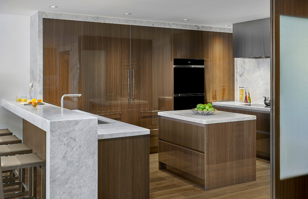 Inspiration for a contemporary u-shaped kitchen in Chicago with an undermount sink, flat-panel cabinets, medium wood cabinets, quartzite benchtops, white splashback, stone slab splashback, panelled appliances, medium hardwood floors, with island, brown floor and white benchtop.