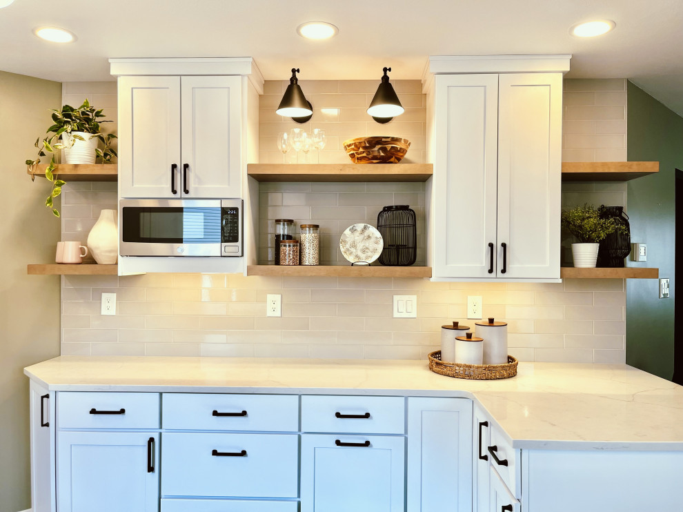 Inspiration for a mid-sized transitional l-shaped vinyl floor and black floor eat-in kitchen remodel with a farmhouse sink, shaker cabinets, white cabinets, quartz countertops, gray backsplash, ceramic backsplash, stainless steel appliances, a peninsula and gray countertops