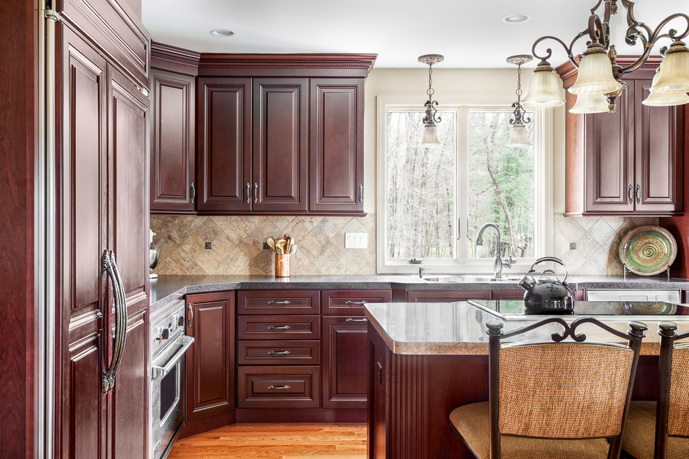 Large traditional l-shaped eat-in kitchen in Boston with raised-panel cabinets, dark wood cabinets, granite benchtops, beige splashback, stone tile splashback and with island.