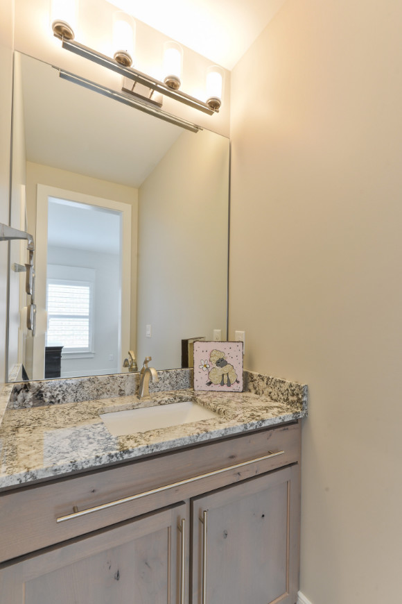 Photo of a transitional powder room in Louisville with shaker cabinets, distressed cabinets, beige walls, an undermount sink, granite benchtops and grey benchtops.
