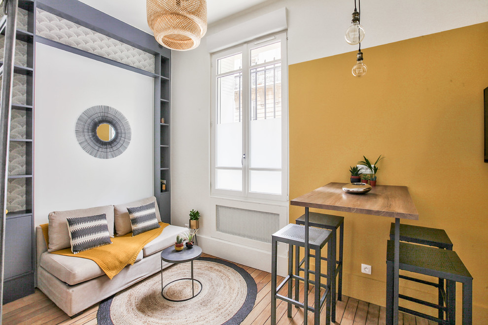 Design ideas for a mid-sized industrial open concept living room in Paris with yellow walls, medium hardwood floors, no fireplace, brown floor, a library and a wall-mounted tv.