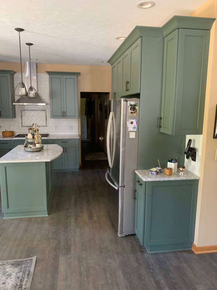 Mid-sized elegant l-shaped medium tone wood floor and brown floor eat-in kitchen photo in Cleveland with an undermount sink, shaker cabinets, green cabinets, quartz countertops, white backsplash, subway tile backsplash, stainless steel appliances, an island and white countertops
