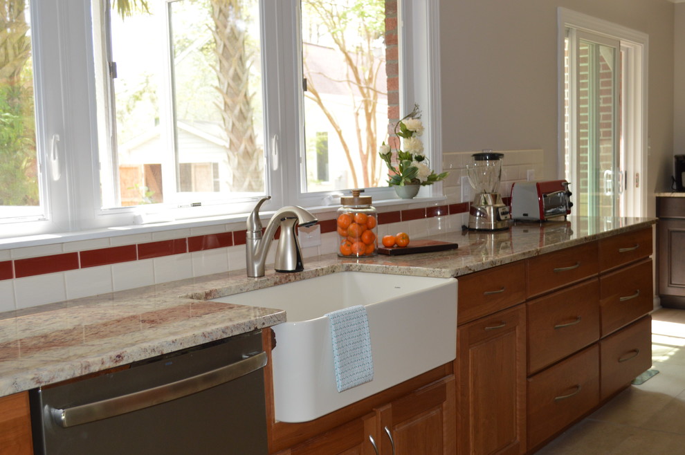 Example of a large transitional l-shaped porcelain tile and beige floor eat-in kitchen design with a farmhouse sink, raised-panel cabinets, brown cabinets, granite countertops, white backsplash, ceramic backsplash, stainless steel appliances and a peninsula