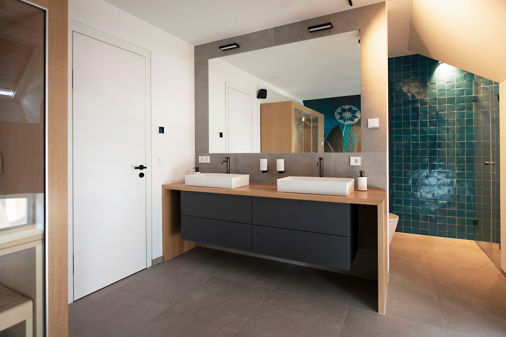 Exemple d'une grande salle de bain tendance avec des portes de placard noires, une baignoire indépendante, une douche à l'italienne, un carrelage bleu, carreaux de ciment au sol, une vasque, un sol gris, une cabine de douche à porte battante, un plan de toilette noir, un banc de douche, meuble double vasque et meuble-lavabo encastré.