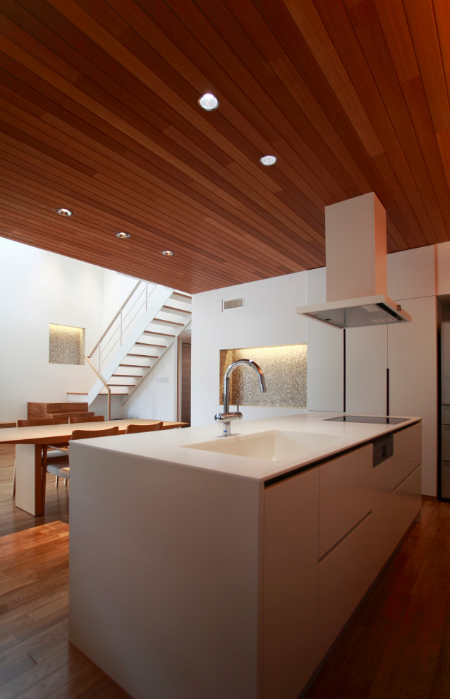 Photo of a modern single-wall open plan kitchen in Other with an integrated sink, flat-panel cabinets, solid surface benchtops, with island and white benchtop.