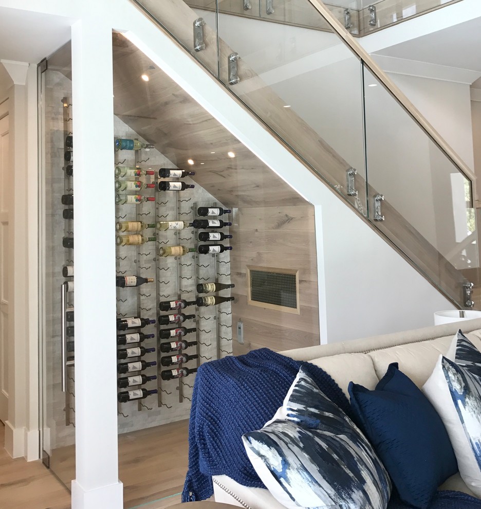 Mid-sized beach style wine cellar in Other with light hardwood floors, storage racks and beige floor.