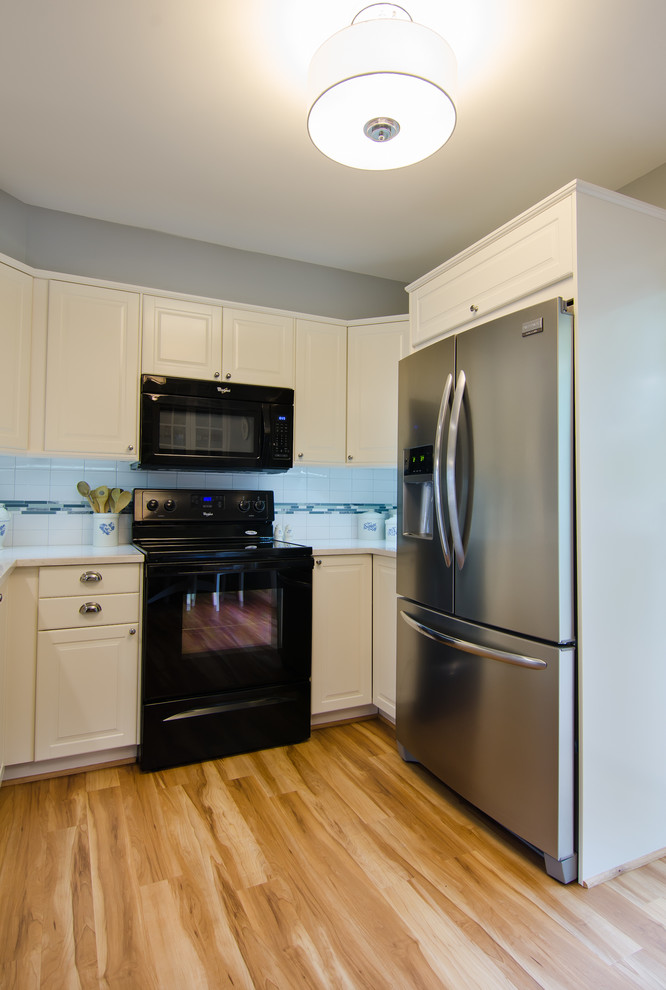 Inspiration for a mid-sized transitional l-shaped vinyl floor enclosed kitchen remodel in DC Metro with an undermount sink, shaker cabinets, quartz countertops, white backsplash, ceramic backsplash, black appliances and no island