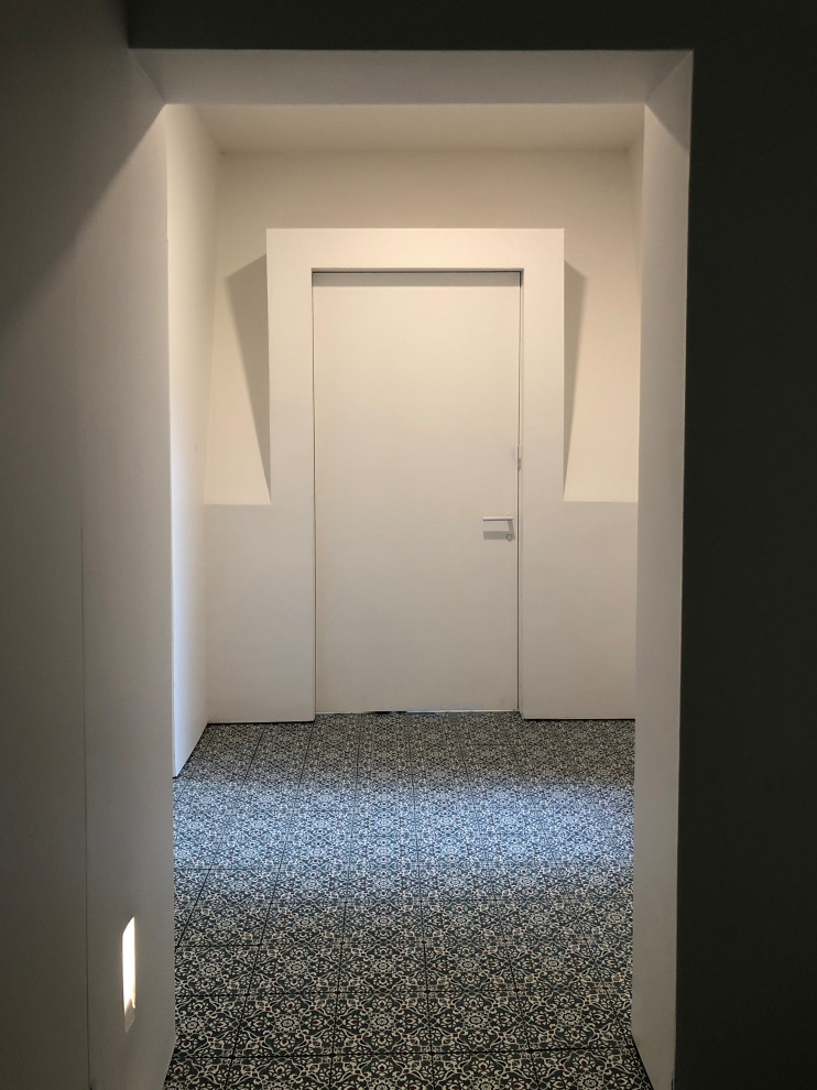 Cette image montre un couloir de taille moyenne avec un mur blanc, un sol en carrelage de porcelaine et un sol bleu.