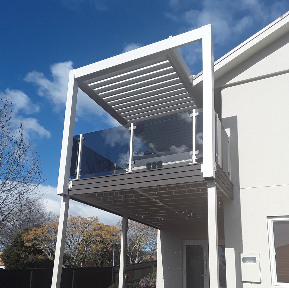This is an example of a modern metal railing balcony in Other with a pergola.