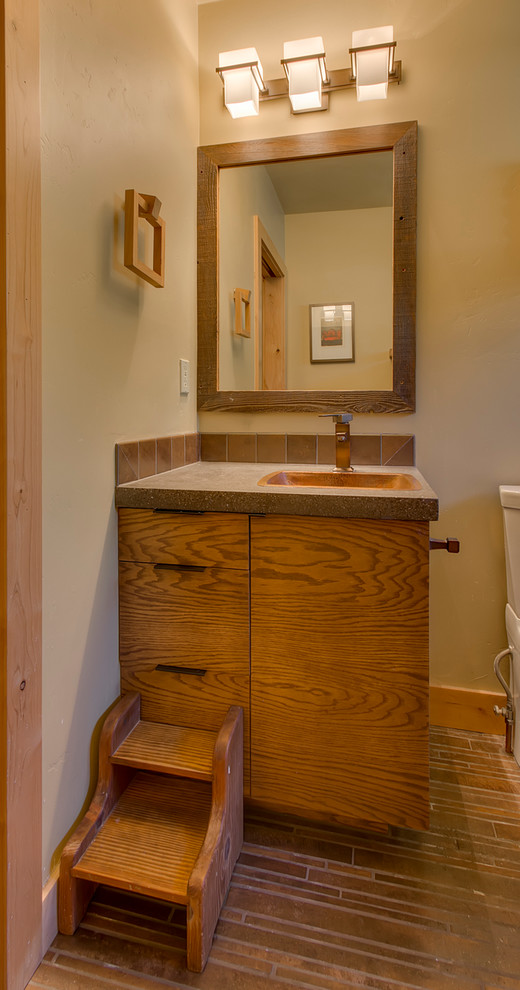 Example of a mid-sized mountain style 3/4 beige tile, brown tile and ceramic tile porcelain tile and brown floor bathroom design with flat-panel cabinets, medium tone wood cabinets, a one-piece toilet, beige walls, a drop-in sink and concrete countertops