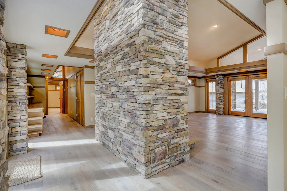 Example of a light wood floor, brown floor and vaulted ceiling double front door design with a medium wood front door