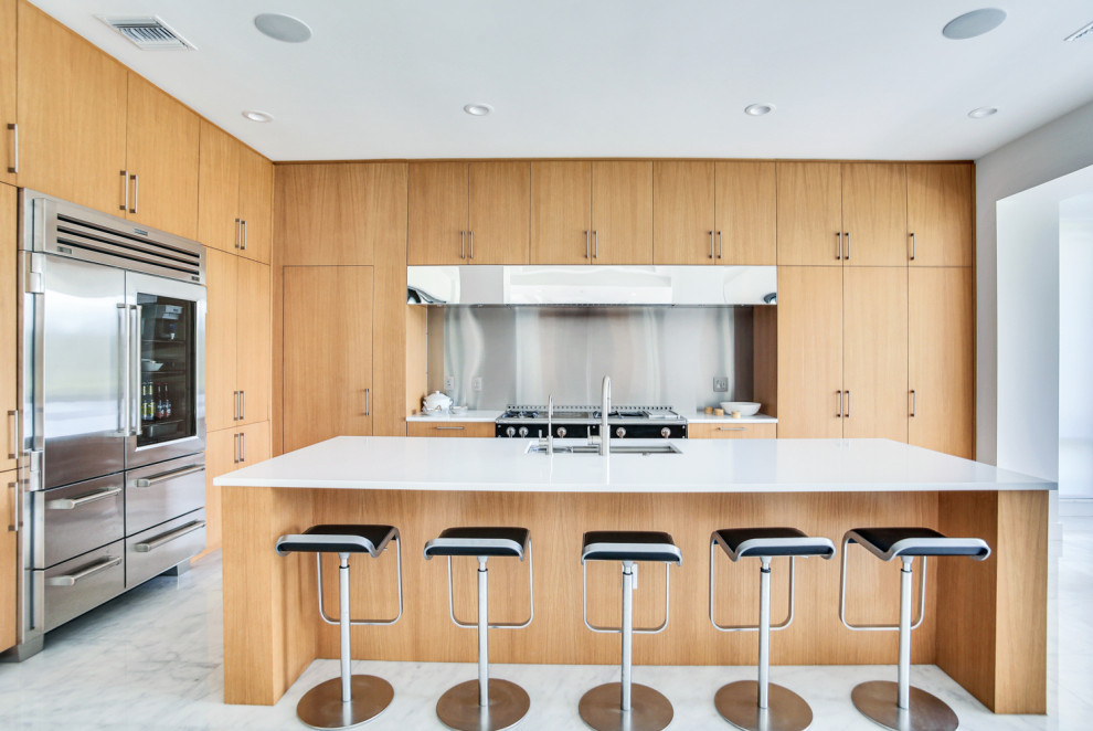 This is an example of a large contemporary l-shaped eat-in kitchen in Tampa with an undermount sink, flat-panel cabinets, light wood cabinets, quartzite benchtops, stainless steel appliances, marble floors, with island, white floor, white benchtop and metallic splashback.