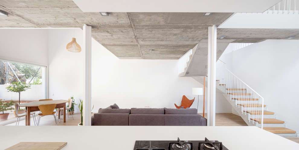 Foto de sala de estar abierta actual de tamaño medio con paredes blancas, suelo de madera clara, vigas vistas y alfombra