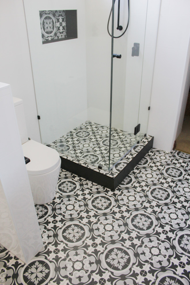 This is an example of a large modern master bathroom in Perth with flat-panel cabinets, dark wood cabinets, a corner shower, a one-piece toilet, white tile, ceramic tile, white walls, ceramic floors, a vessel sink, engineered quartz benchtops, multi-coloured floor, a hinged shower door and white benchtops.