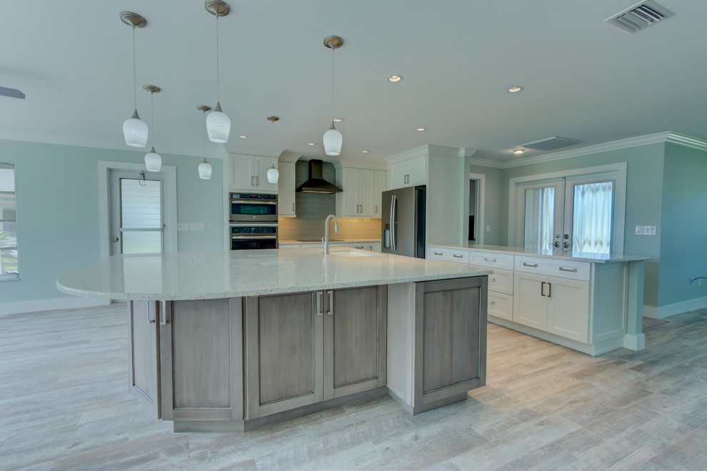 This is an example of a large transitional l-shaped open plan kitchen in Other with an undermount sink, shaker cabinets, white cabinets, recycled glass benchtops, blue splashback, glass tile splashback, stainless steel appliances, ceramic floors, with island, grey floor and white benchtop.