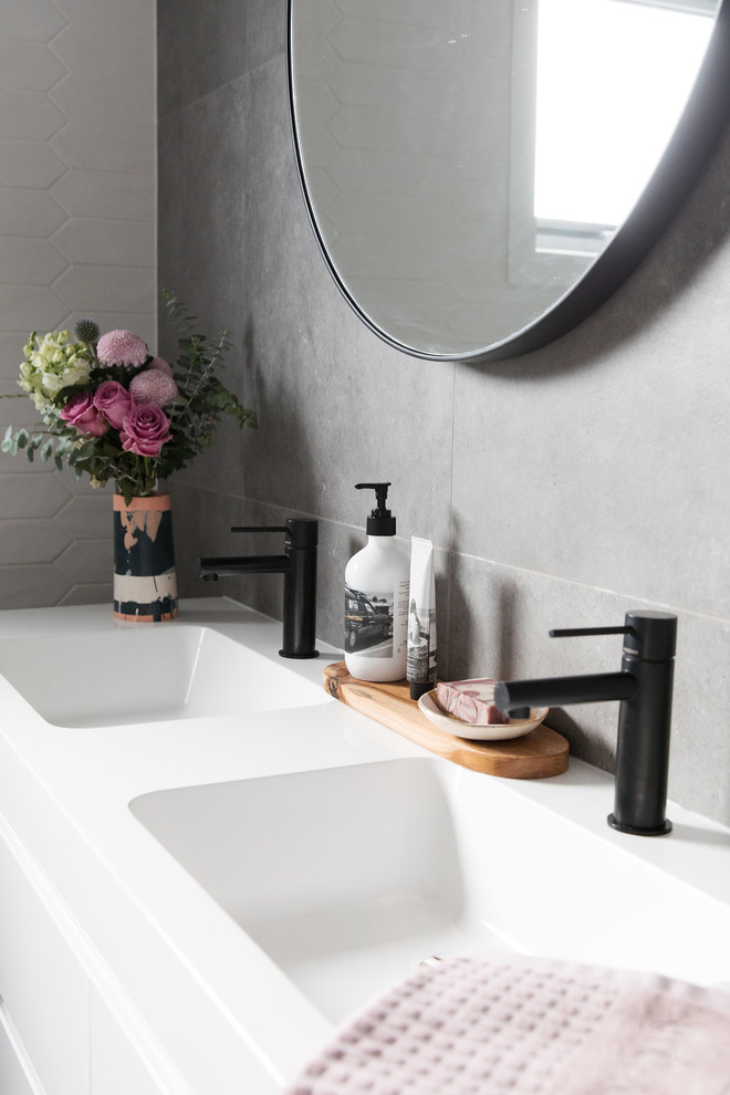 Inspiration for a mid-sized modern 3/4 bathroom in Canberra - Queanbeyan with furniture-like cabinets, white cabinets, a drop-in tub, a one-piece toilet, gray tile, porcelain tile, grey walls, porcelain floors, an undermount sink and grey floor.