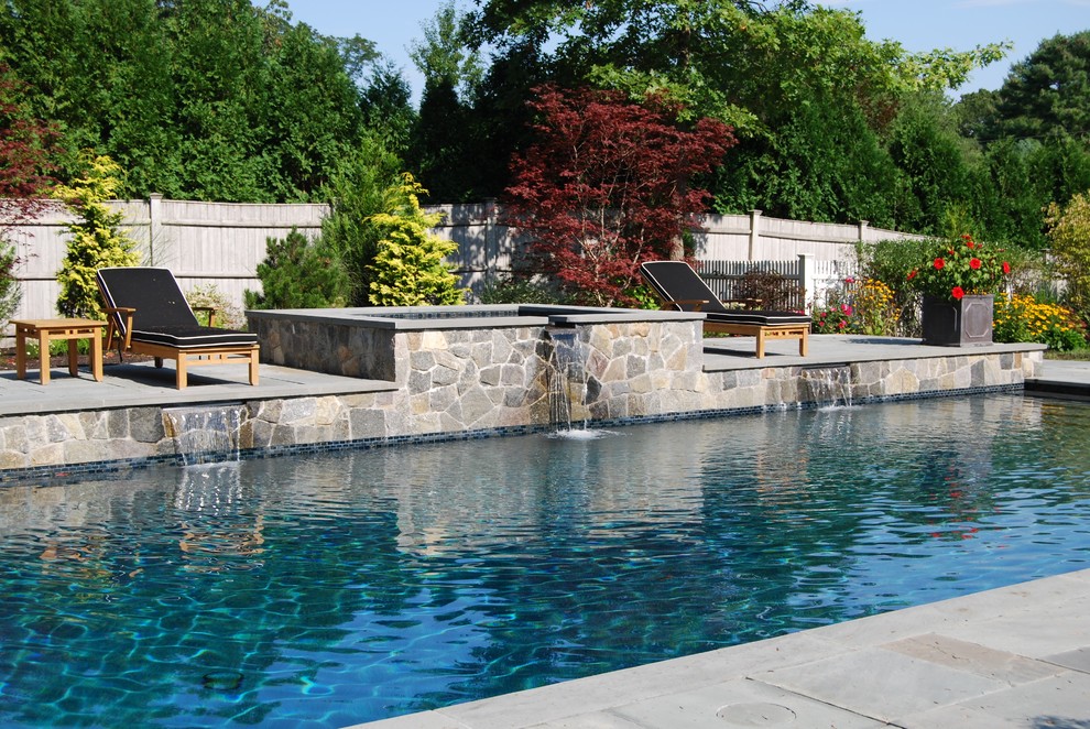 This is an example of a mid-sized traditional backyard rectangular lap pool in Boston with a hot tub and natural stone pavers.