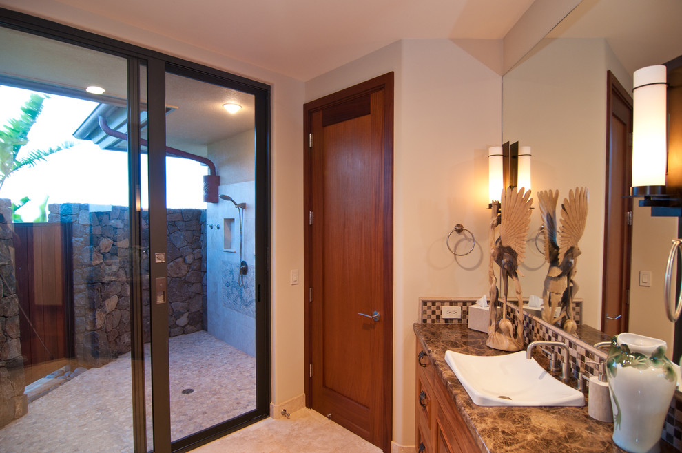 Mid-sized tropical master bathroom in Hawaii with an open shower, raised-panel cabinets, medium wood cabinets, an open shower, beige tile, brown tile, mosaic tile, beige walls, ceramic floors, a vessel sink, granite benchtops and beige floor.