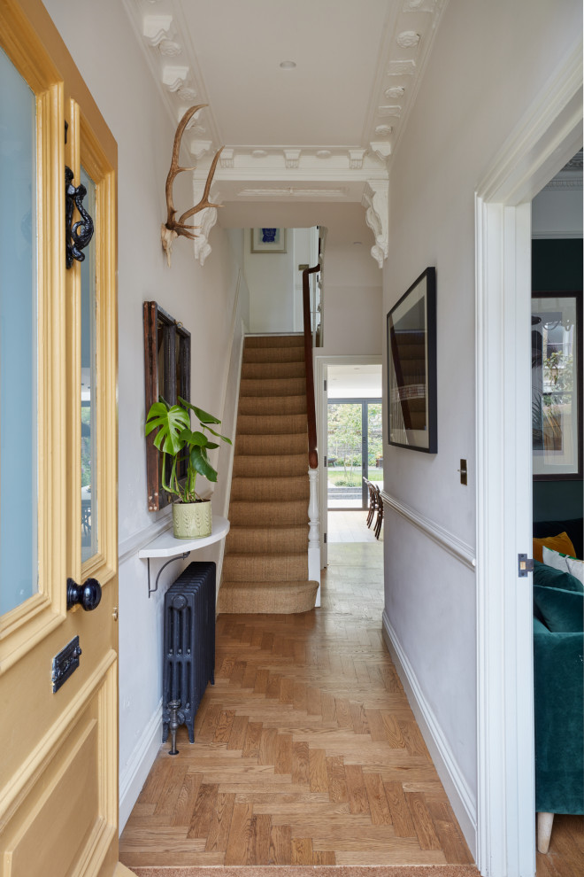 Design ideas for a mid-sized eclectic hallway in London with white walls, light hardwood floors and brick walls.