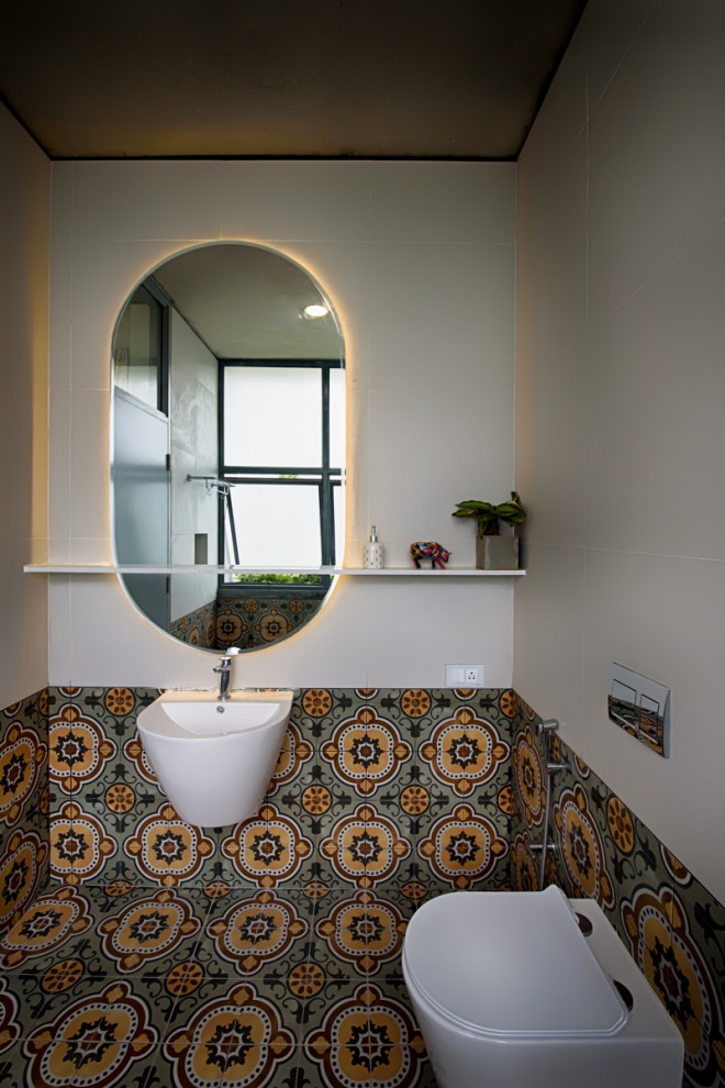 This is an example of a contemporary powder room in Bengaluru with a wall-mount toilet, multi-coloured tile, white walls, a wall-mount sink and multi-coloured floor.