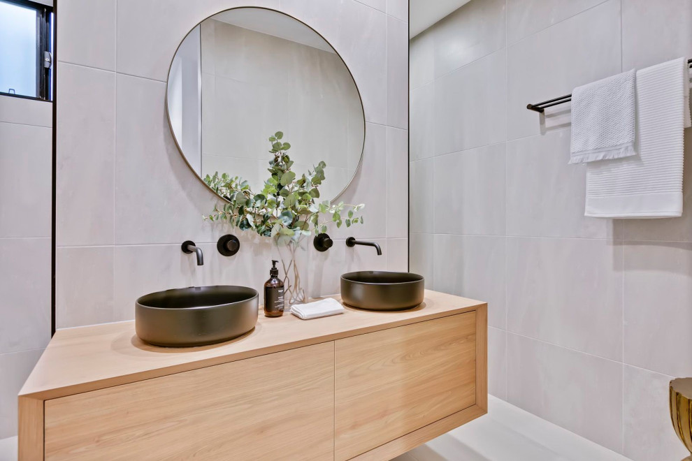 Contemporary bathroom in Sunshine Coast with flat-panel cabinets, light wood cabinets, gray tile, grey walls, a vessel sink, wood benchtops, white floor, a double vanity and a floating vanity.