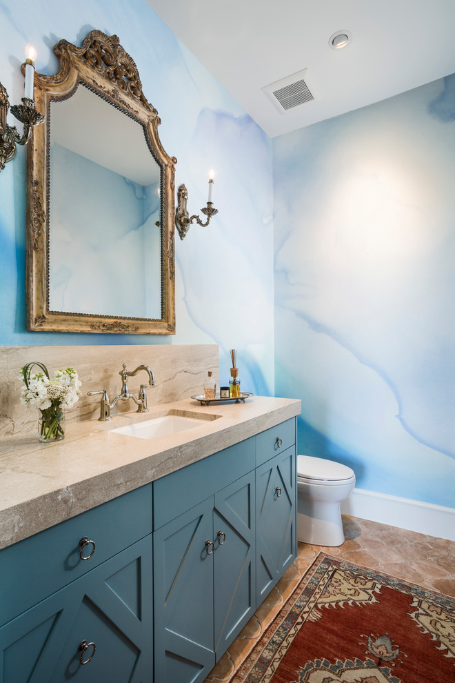 Design ideas for a mid-sized transitional powder room in Austin with recessed-panel cabinets, blue cabinets, blue tile, ceramic tile, white walls, terra-cotta floors, an undermount sink, marble benchtops, red floor and beige benchtops.