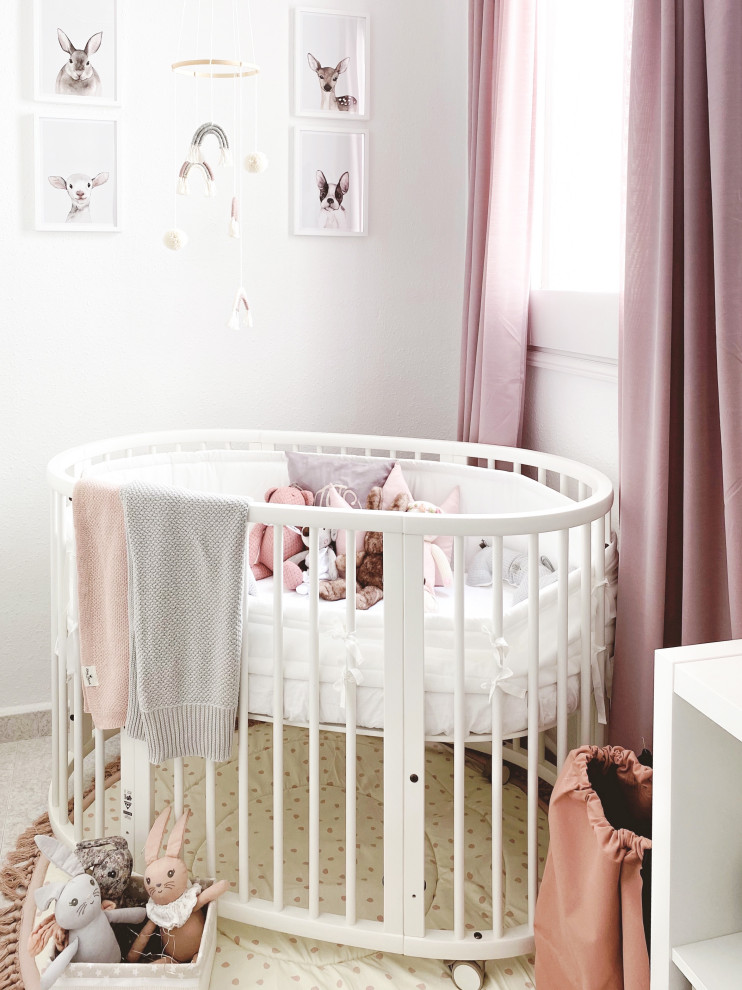 This is an example of a small scandinavian nursery for girls with pink walls, ceramic floors, beige floor and panelled walls.