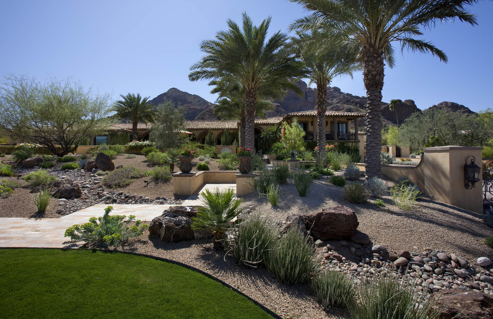 Expansive backyard garden in Phoenix with with rock feature.