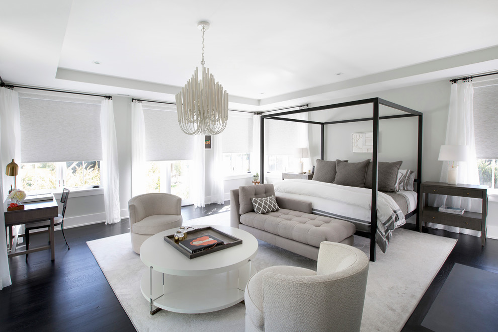 This is an example of a transitional master bedroom in New York with grey walls and dark hardwood floors.