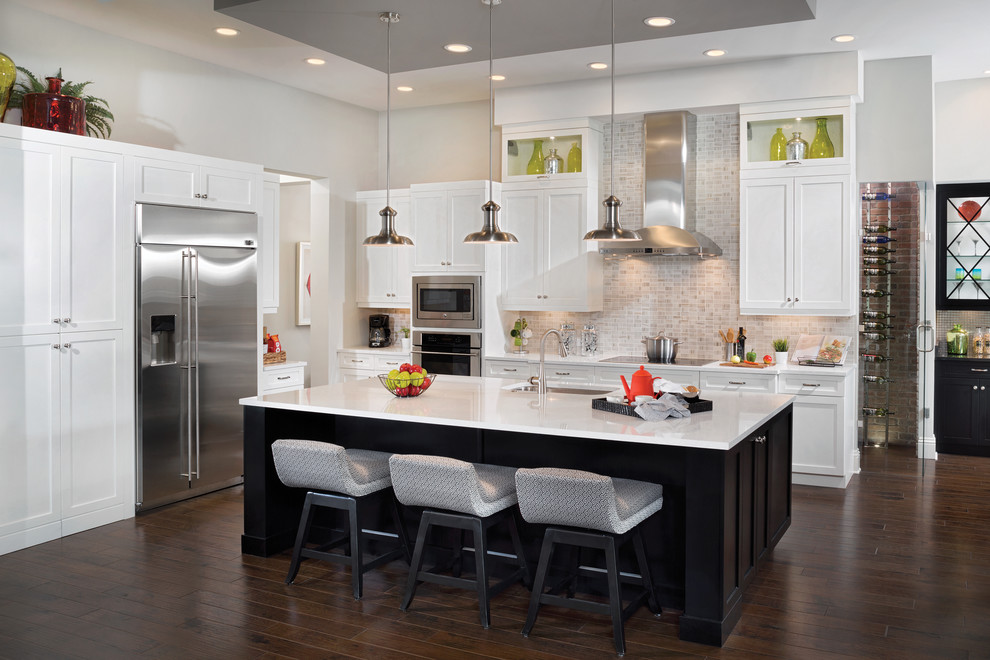 Design ideas for an expansive transitional l-shaped eat-in kitchen in Tampa with an undermount sink, glass-front cabinets, dark wood cabinets, granite benchtops, metallic splashback, glass tile splashback, stainless steel appliances, dark hardwood floors and with island.