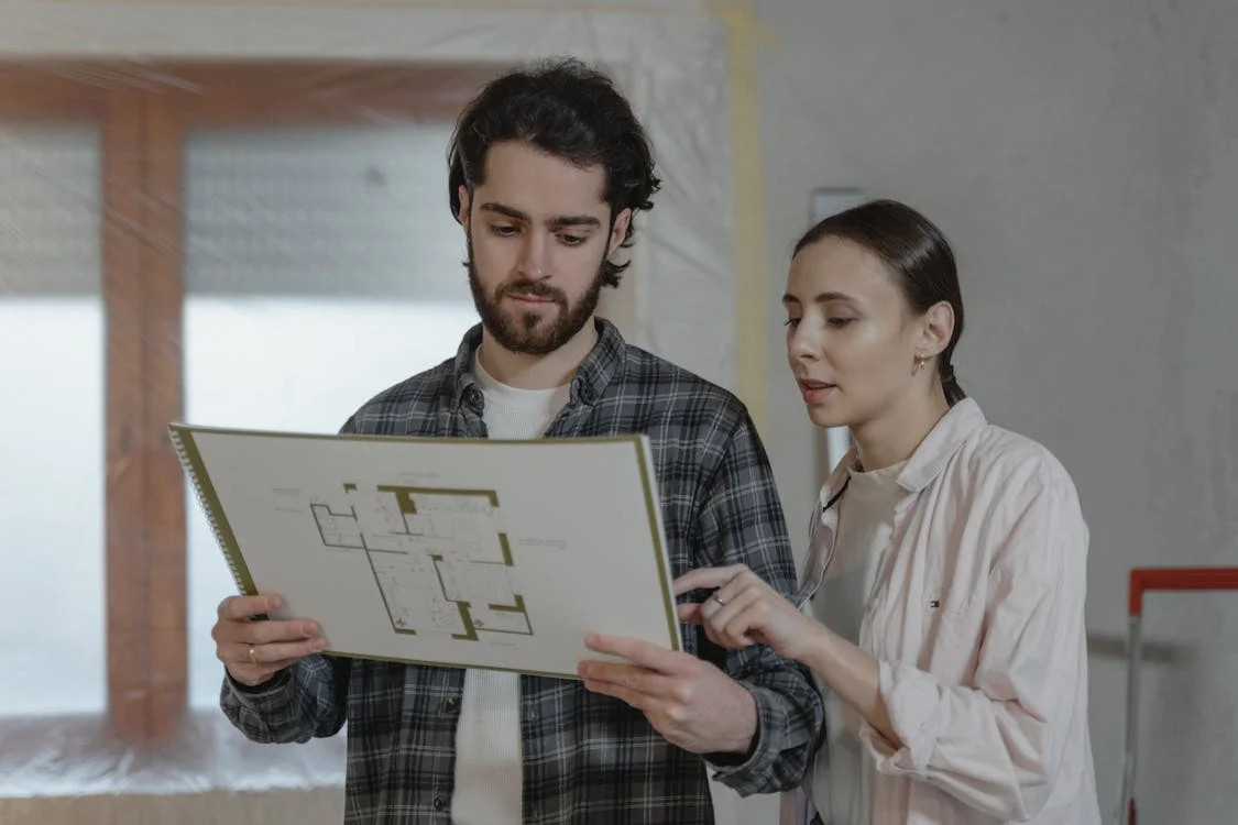 A contractor and homeowner reviewing blueprints together.