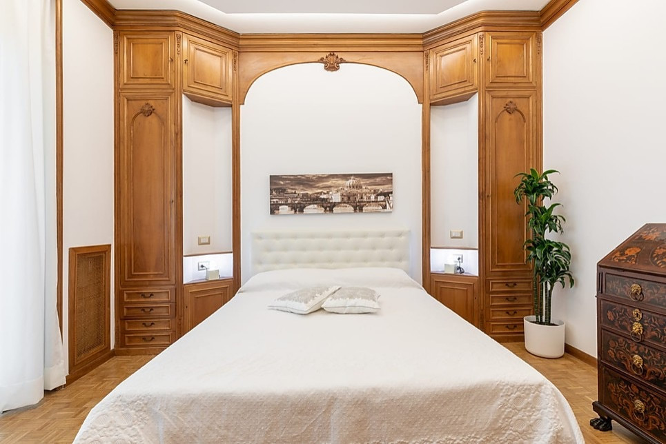 Photo of a large traditional master bedroom in Rome with white walls, medium hardwood floors, no fireplace and brown floor.