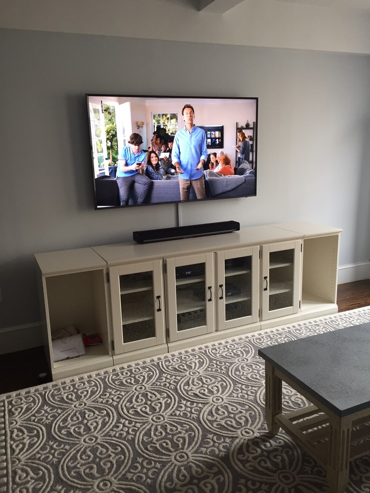 Design ideas for a mid-sized transitional enclosed home theatre in New York with blue walls, dark hardwood floors, a wall-mounted tv and brown floor.