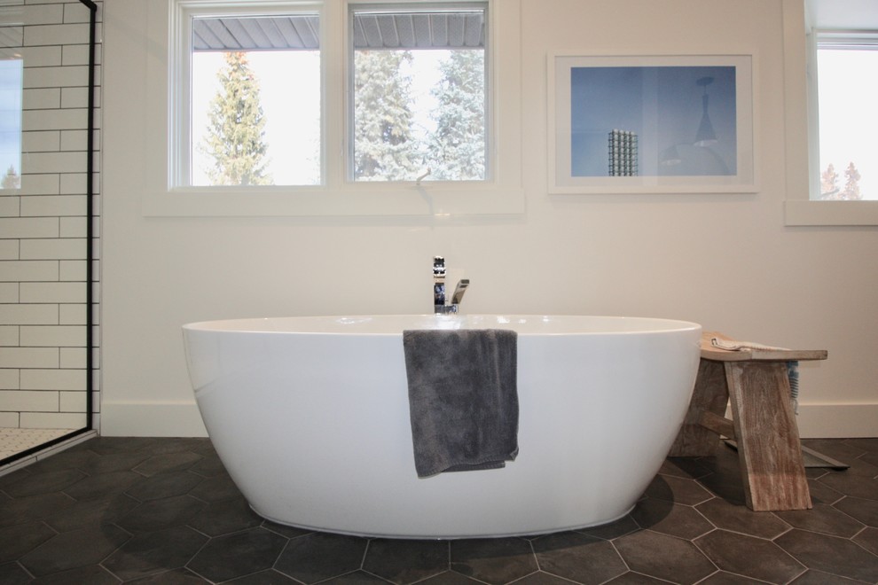 Inspiration for a mid-sized contemporary master bathroom in Calgary with flat-panel cabinets, light wood cabinets, a freestanding tub, an alcove shower, subway tile, white walls, cement tiles, a vessel sink, solid surface benchtops, grey floor, a hinged shower door and white benchtops.