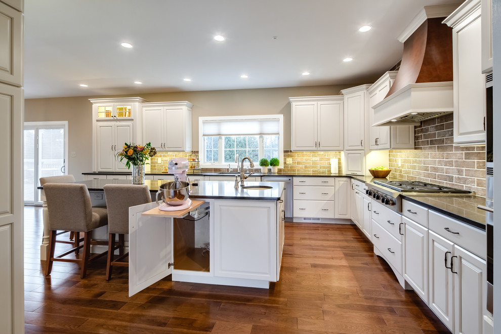 Inspiration for a large transitional eat-in kitchen in Philadelphia with an undermount sink, raised-panel cabinets, white cabinets, quartz benchtops, brown splashback, ceramic splashback, stainless steel appliances, medium hardwood floors and with island.