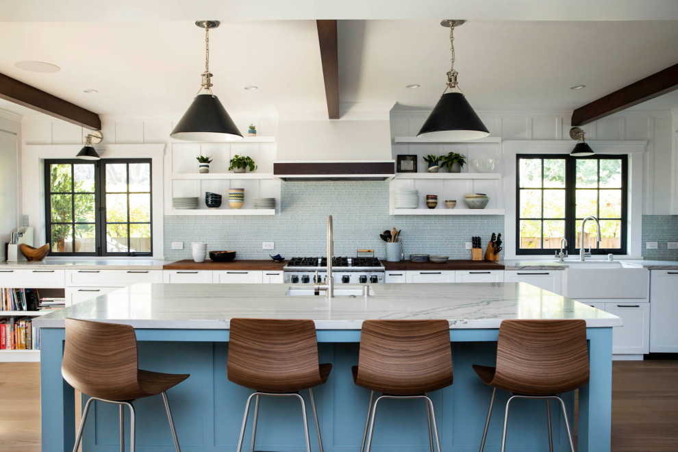 Inspiration for a large transitional galley open plan kitchen in San Francisco with a farmhouse sink, shaker cabinets, white cabinets, quartzite benchtops, blue splashback, glass tile splashback, with island, stainless steel appliances, medium hardwood floors, brown floor, grey benchtop and exposed beam.