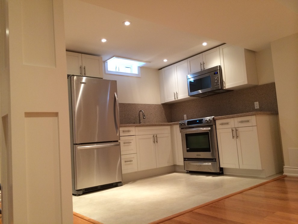 Mid-sized transitional l-shaped porcelain tile kitchen photo in Toronto with shaker cabinets, white cabinets, a double-bowl sink, granite countertops, beige backsplash, stone tile backsplash and black appliances