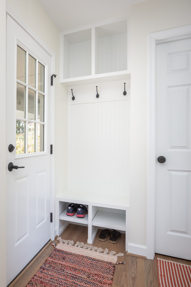 Mid-sized transitional medium tone wood floor, brown floor and wainscoting foyer photo in Raleigh with white walls and a glass front door