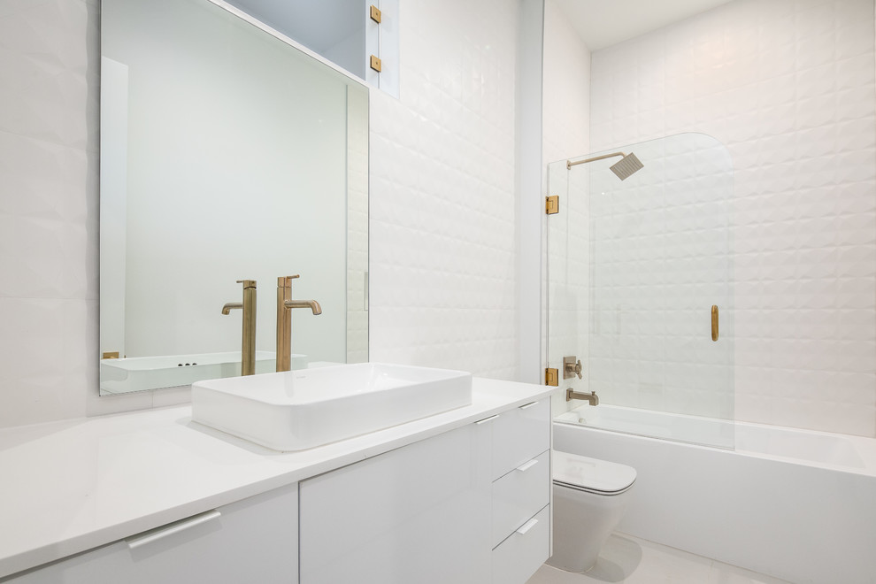Design ideas for a mid-sized modern 3/4 bathroom in Dallas with flat-panel cabinets, white cabinets, an alcove tub, a shower/bathtub combo, a one-piece toilet, white tile, ceramic tile, white walls, a vessel sink, engineered quartz benchtops, grey floor, a hinged shower door and white benchtops.